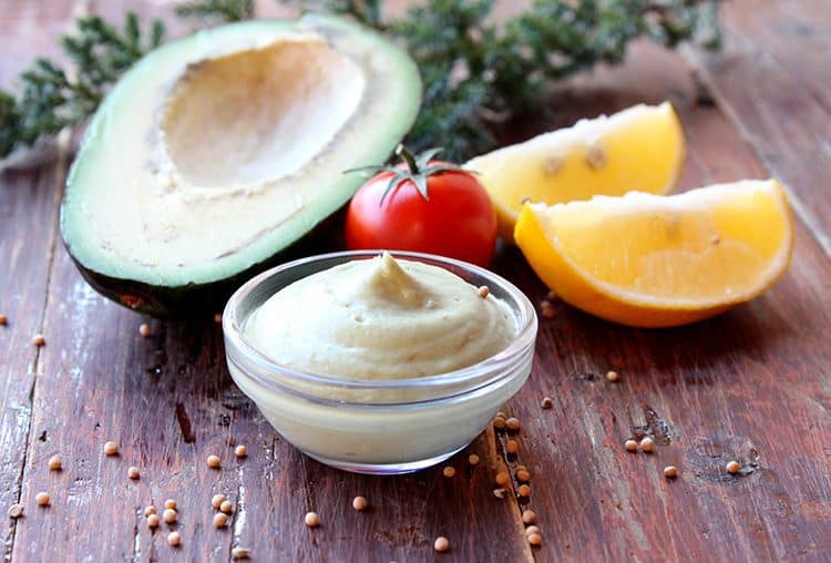 A bowl of avocado mayonnaise with avocado, tomato and lemon slices