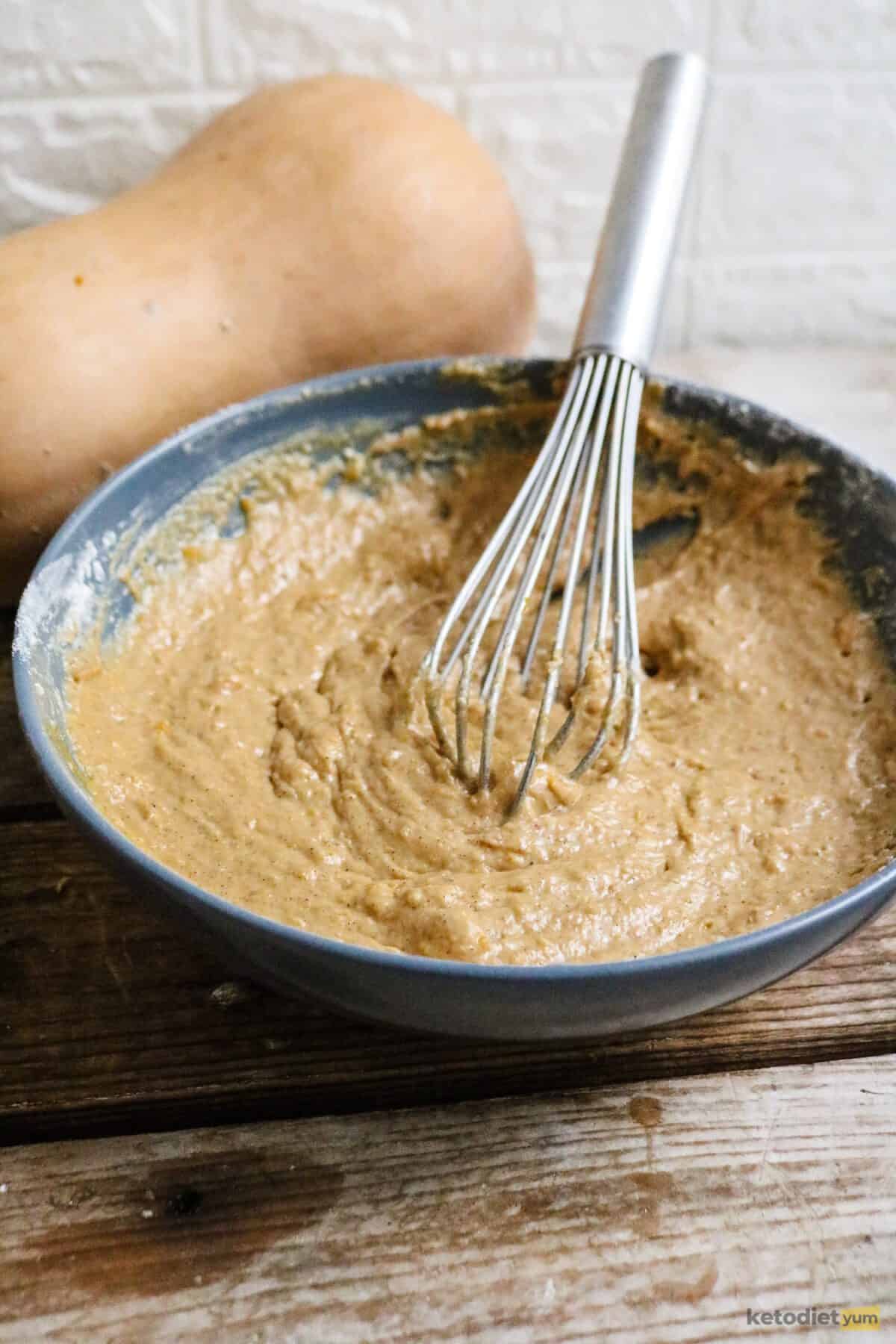 A mixing bowl filled with keto pumpkin bread batter ready to transfer to a lined baking loaf pan
