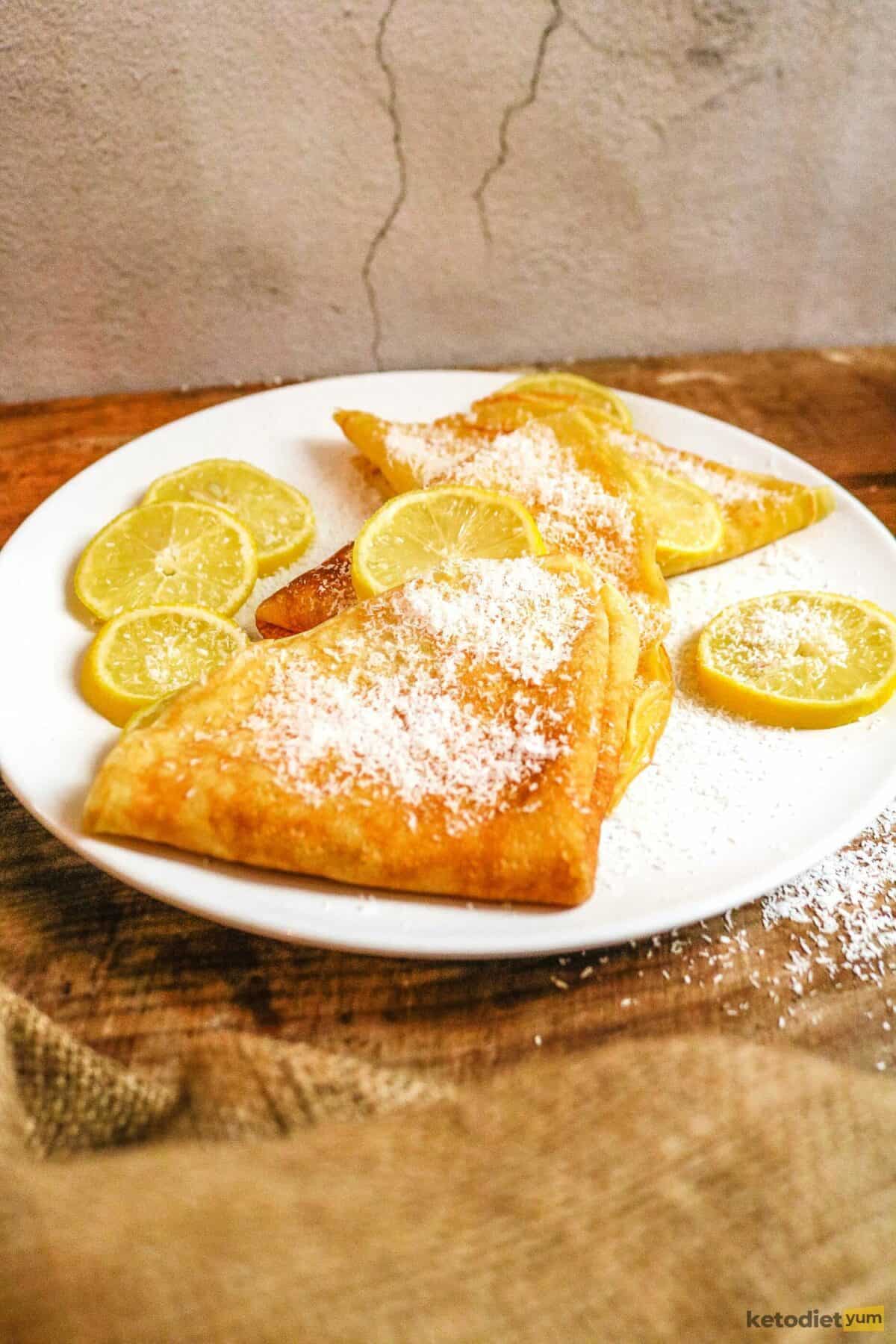 Gluten free crepes on a white plate with lemon and coconut flakes