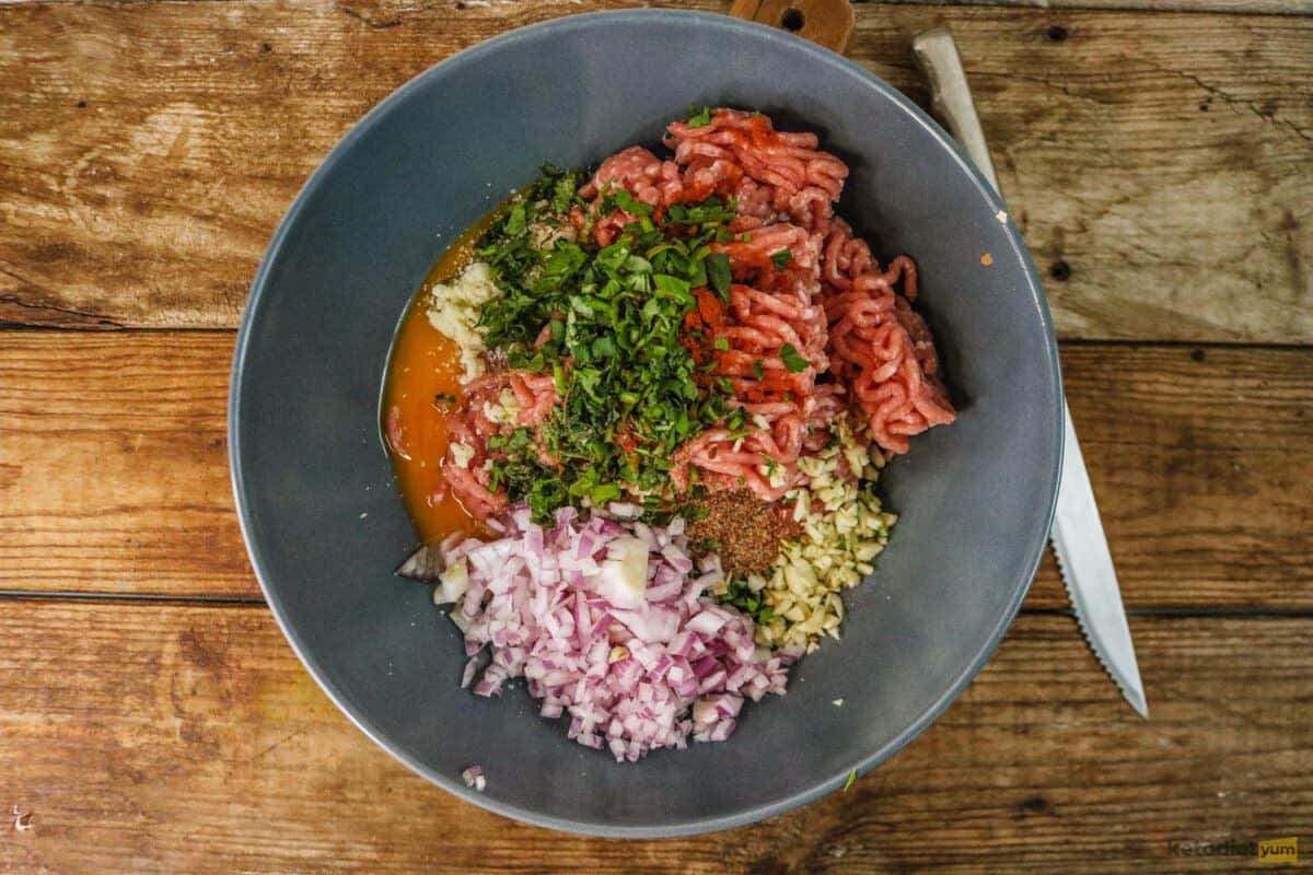 Bowl with ground beef, red onion, parmesan cheese, eggs, garlic, flaxseed, paprika, salt and parsley