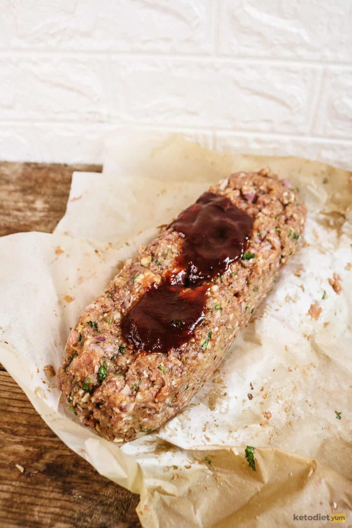 Unbaked meatloaf on baking paper topped with a tomato balsamic glaze