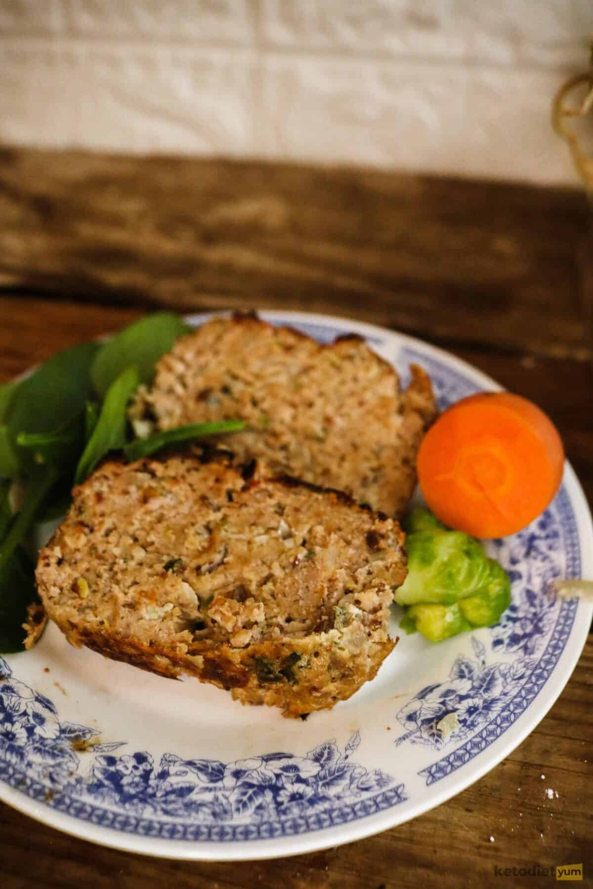 Best Keto Meatloaf Recipe Two slices of meatloaf on a plate with spinach, carrot and broccoli