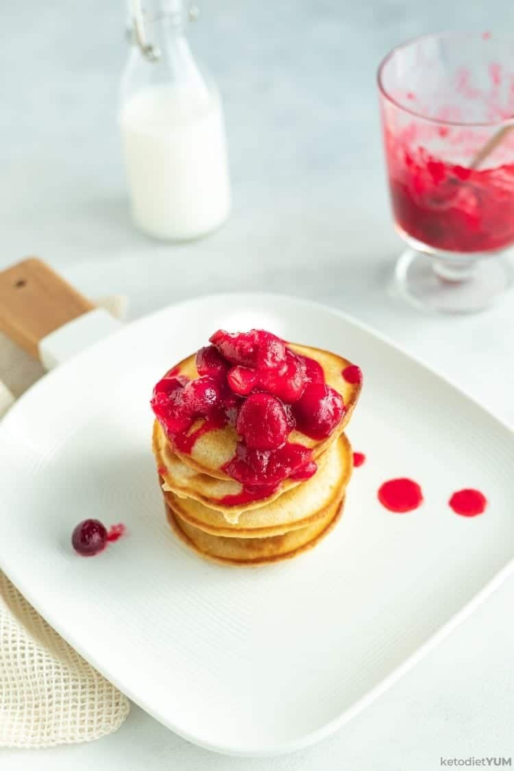 Cranberry Keto Pancakes Recipe A stack of keto pancakes with cranberries on a plate.