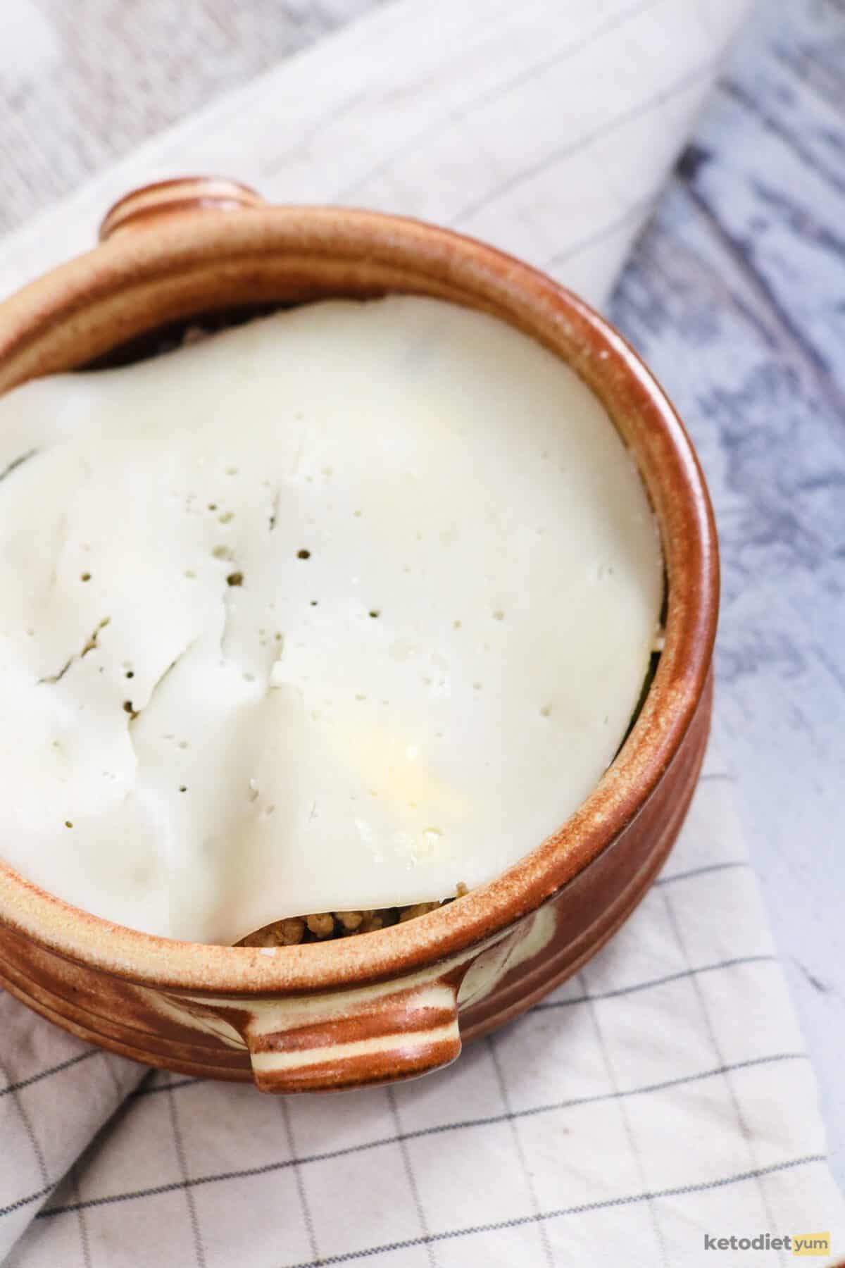 Brown casserole dish topped with slices of provolone cheese