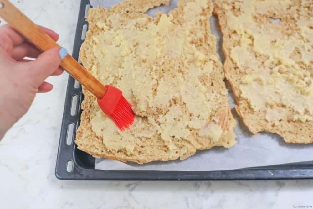 Brushing the cheese topping on parmesan keto croutons