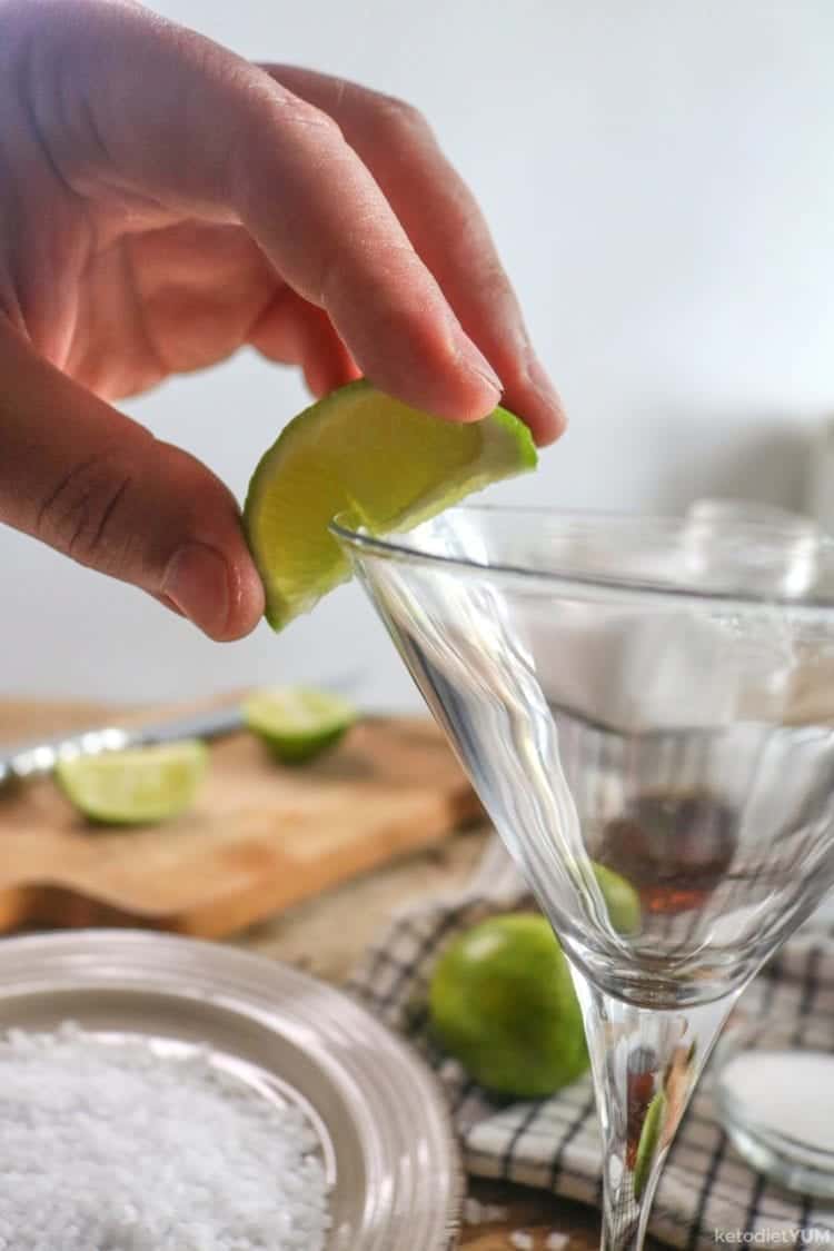 Running lime wedge along the cocktail glass rim