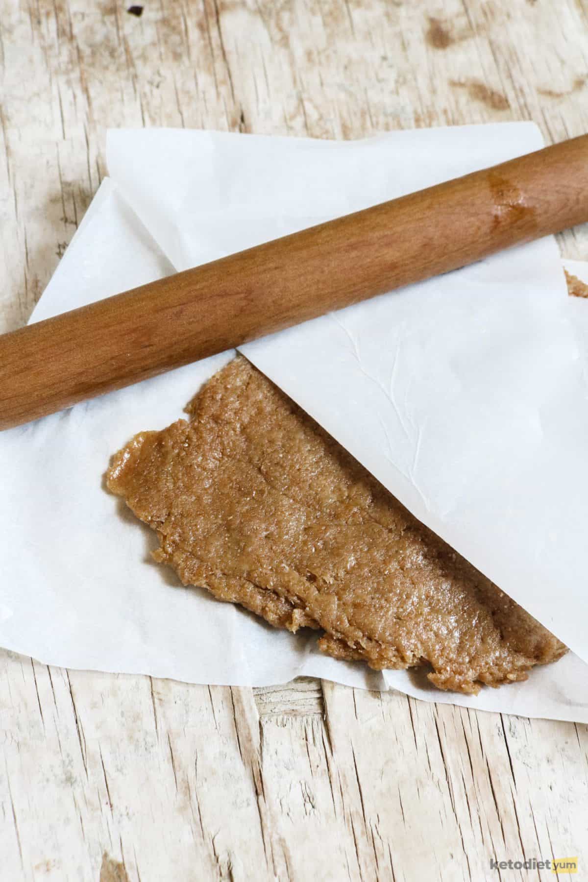 Rolling keto tortilla chip dough between two sheets of baking paper