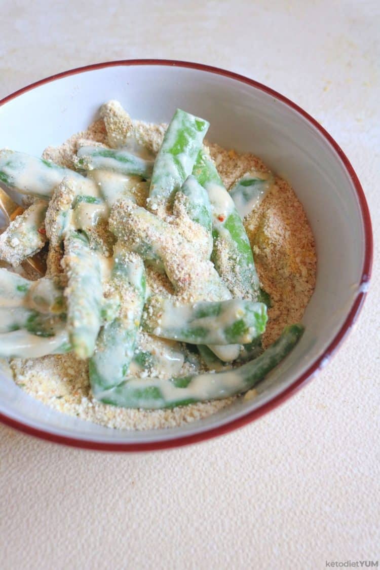 Coating the green beans with the egg and parmesan mixture