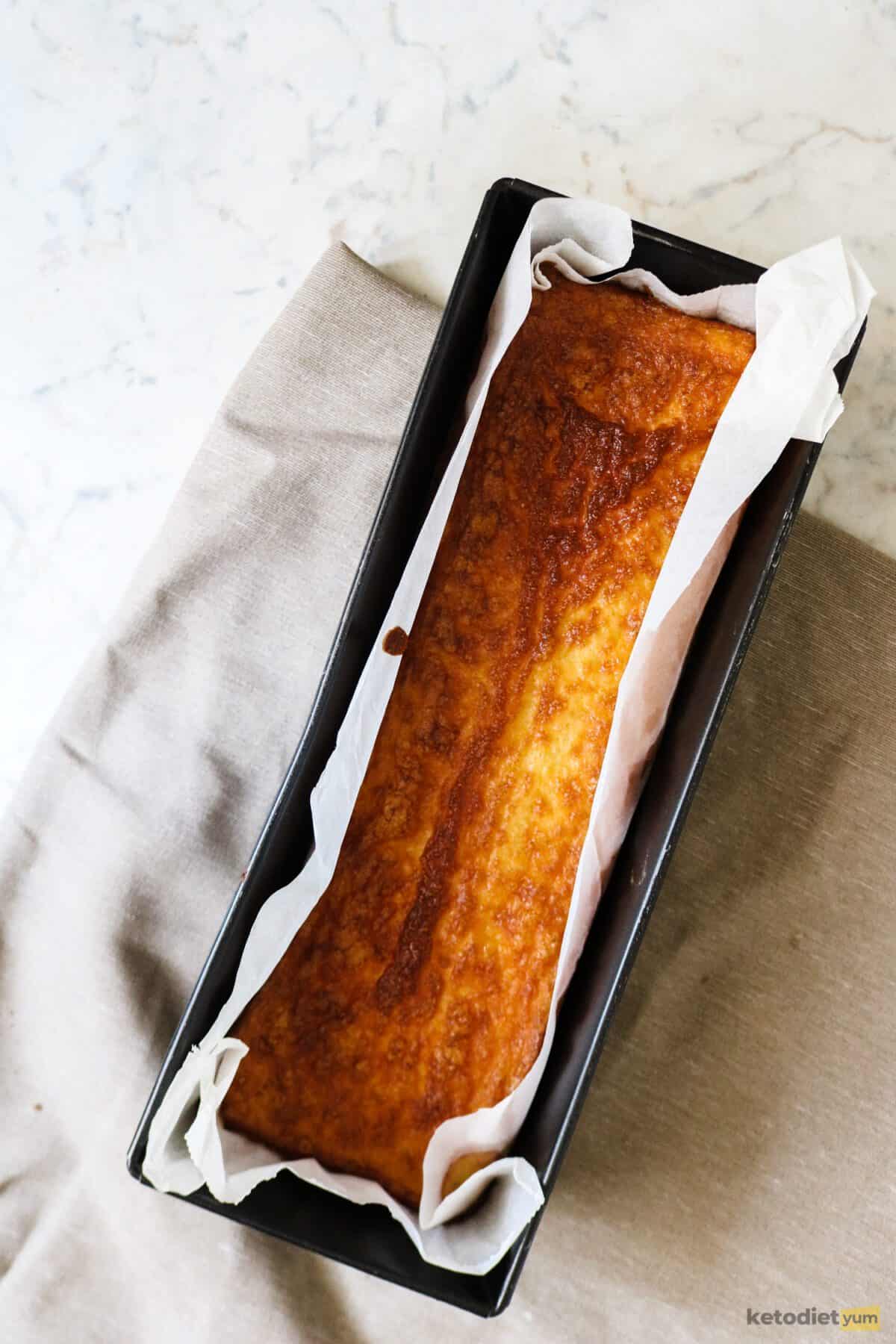 Loaf pan with golden keto egg loaf resting on a table