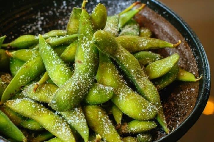 A bowl of edamame in the pod with parmesan cheese