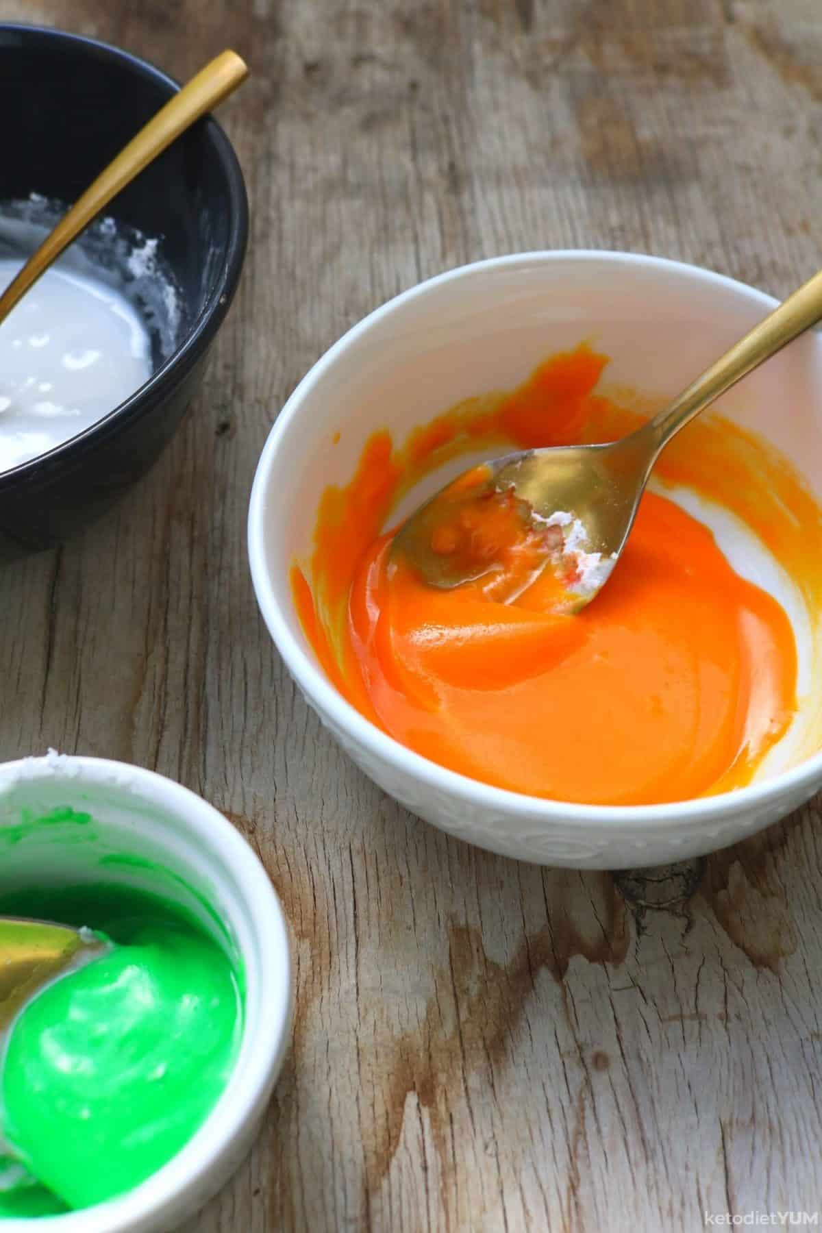 Green, white and orange icing ready to decorate Halloween pumpkin cookies