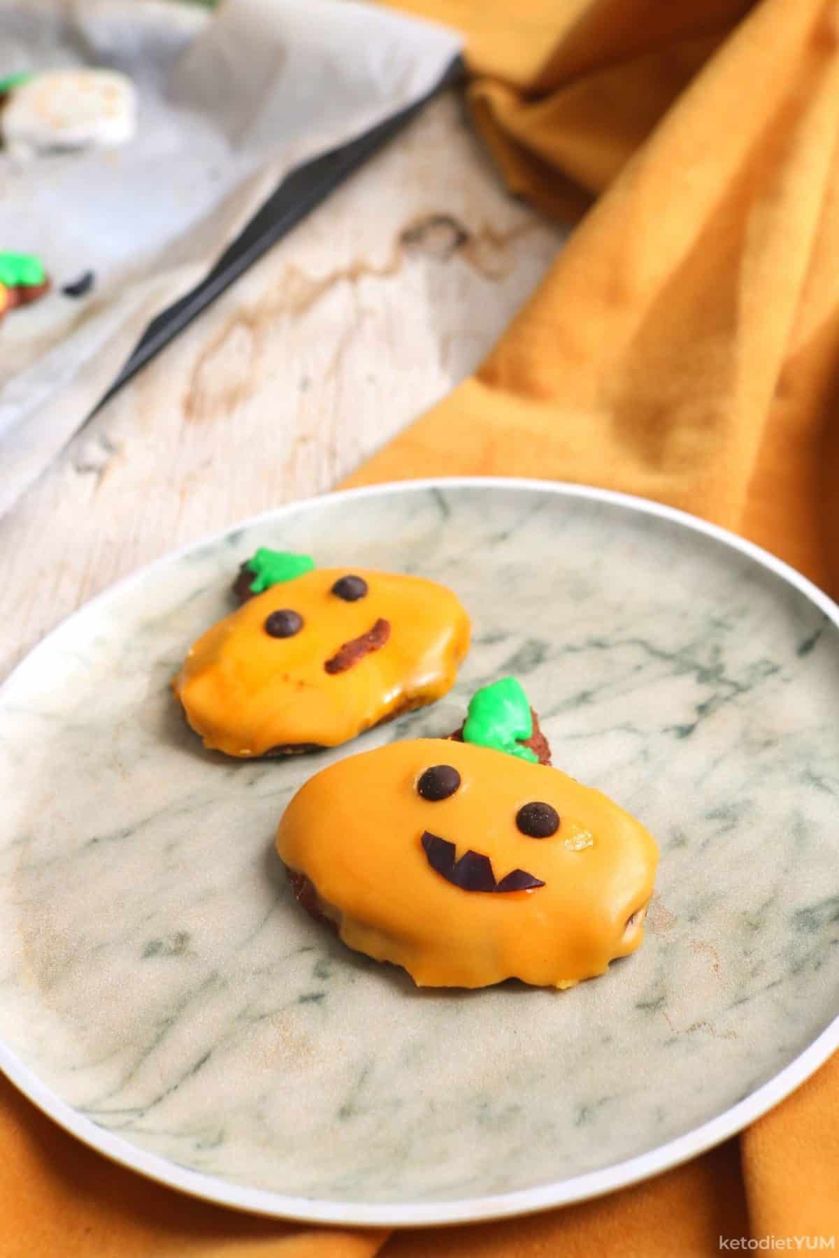 Halloween pumpkin cookies with orange and green icing with chocolate chip eyes and chocolate mouth