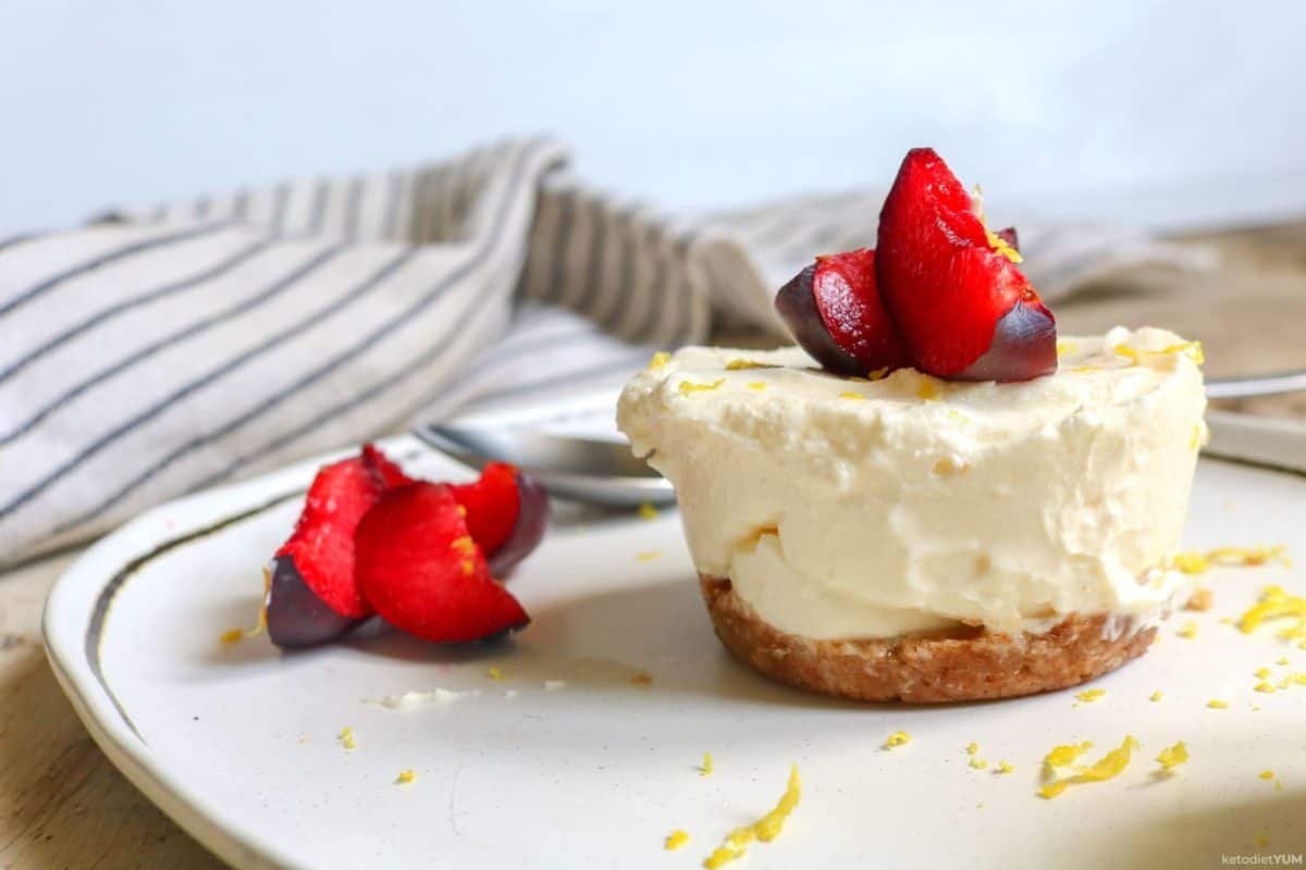 A keto mini cheesecake topped with fresh fruit on a white plate