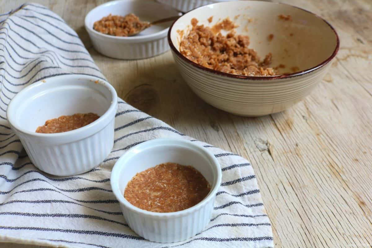Pressing the cheesecake base mixture into individual ramekins