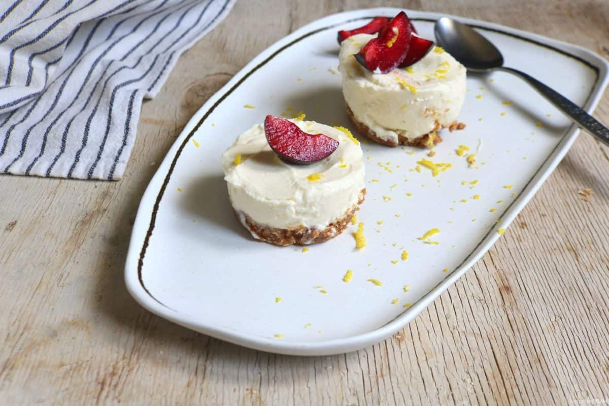 Mini cheesecakes after chilling on a white plate topped with slices of fresh fruit