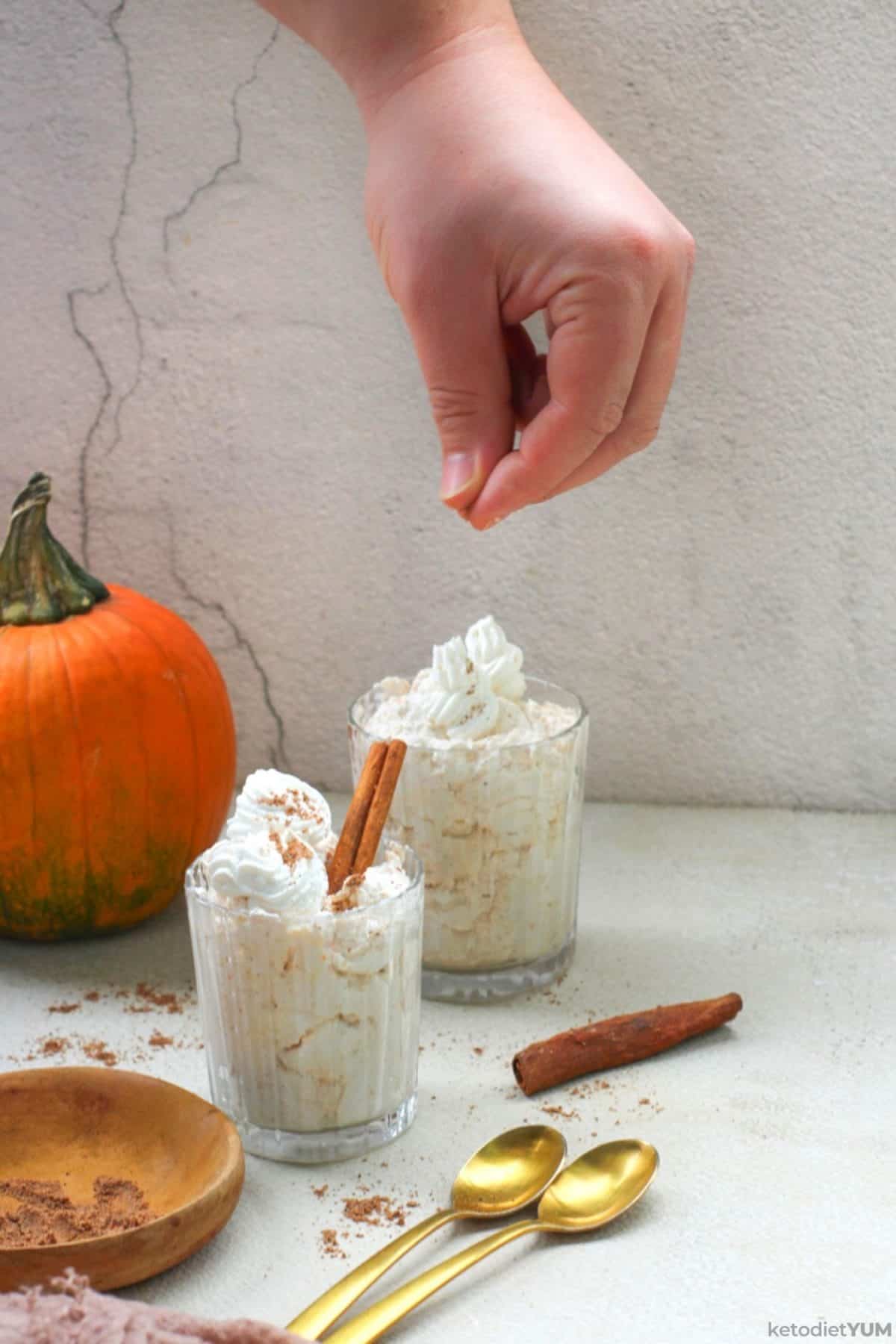 Sprinkling pumpkin pie spice over the keto pumpkin mousse