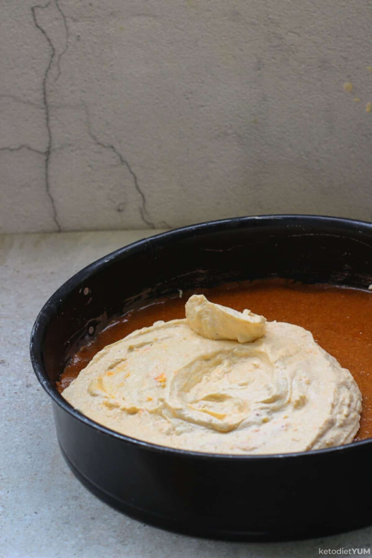 Adding the cream cheese filling mixture on top of the cheesecake base ready to set in the fridge