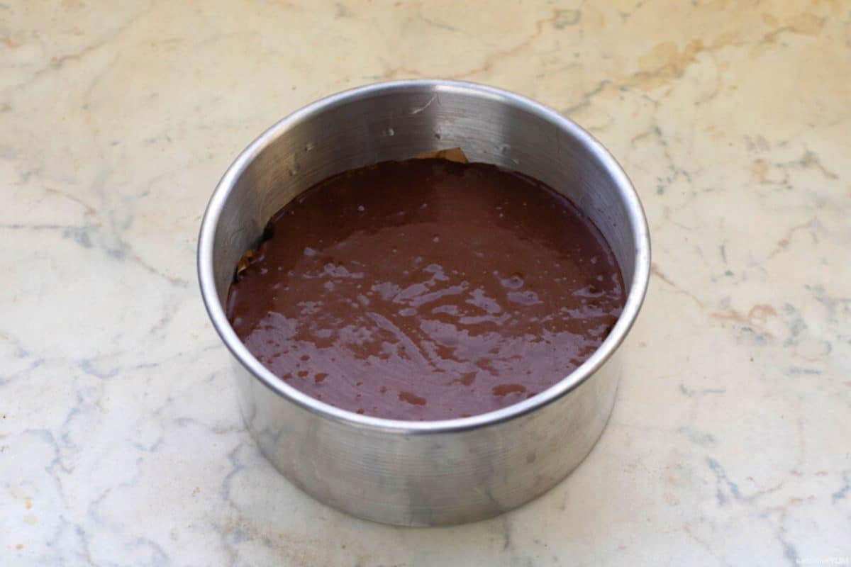 Chocolate cake batter poured into a greased cake pan ready to bake