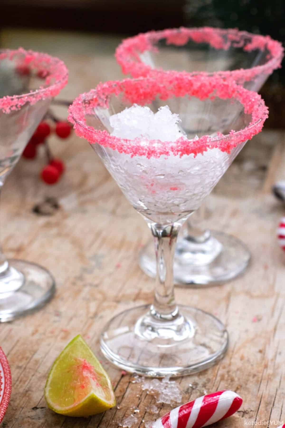 Martini glasses rimmed with festive red Erythritol granules and filled with crushed ice