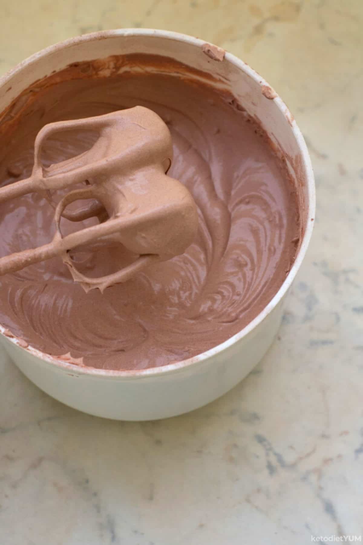 Whisking all the ingredients together with an electric mixer to make our keto chocolate frosting