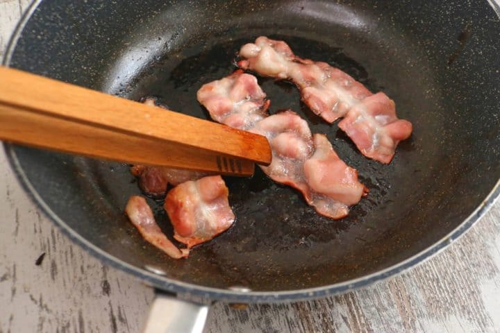 Flipping the bacon with tongs