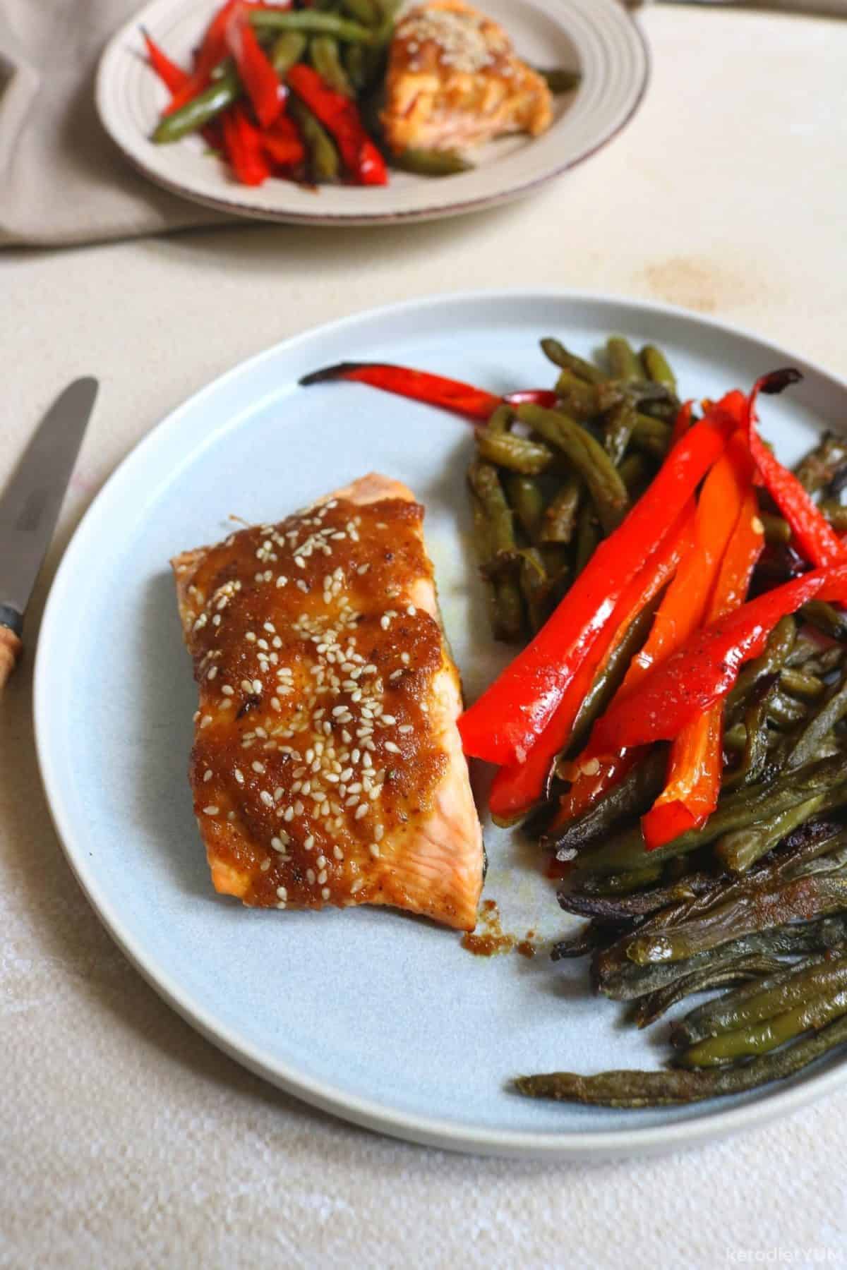 Delicious baked salmon and green beans served on a white plate