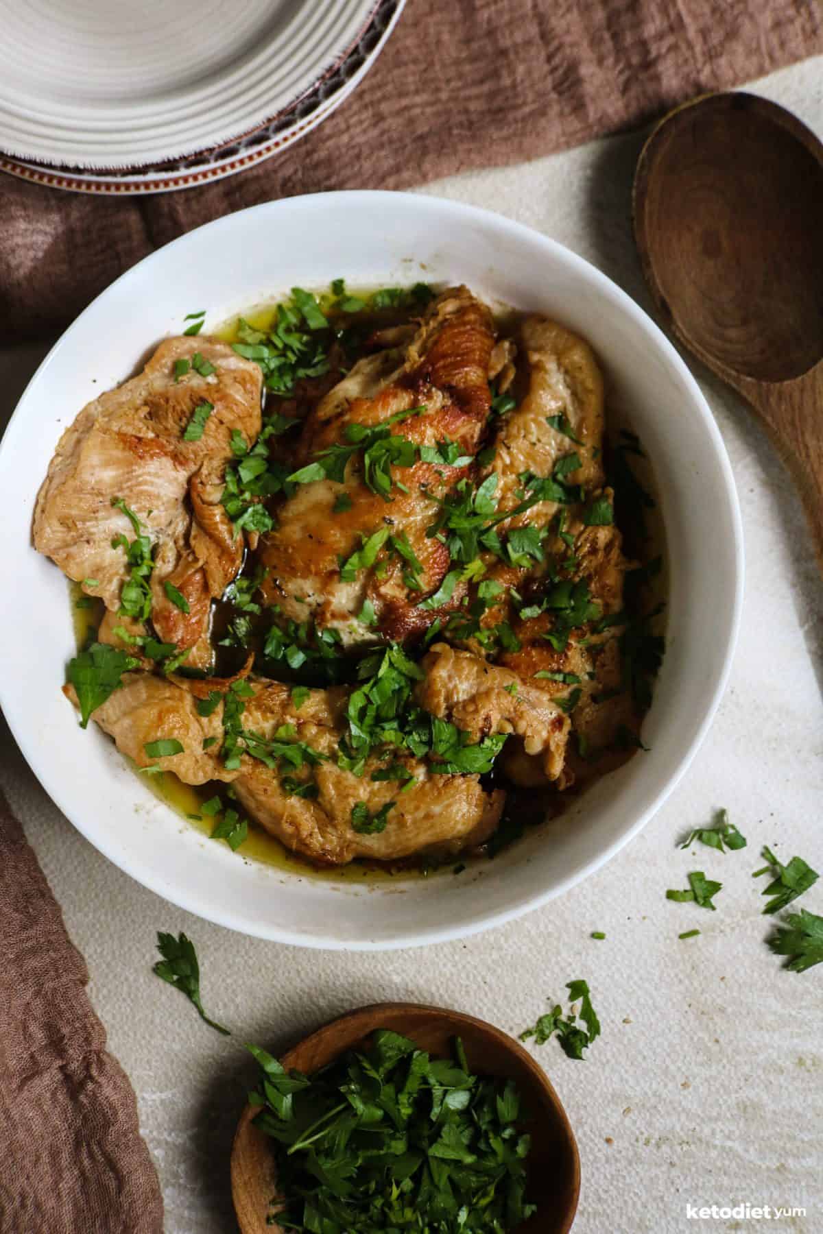 Keto garlic butter chicken garnished with fresh parsley served in a white bowl