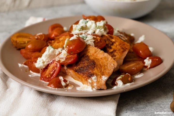 Crispy and juicy pan seared salmon fillets with cherry tomatoes and a salsa cheese sauce on a plate ready to eat