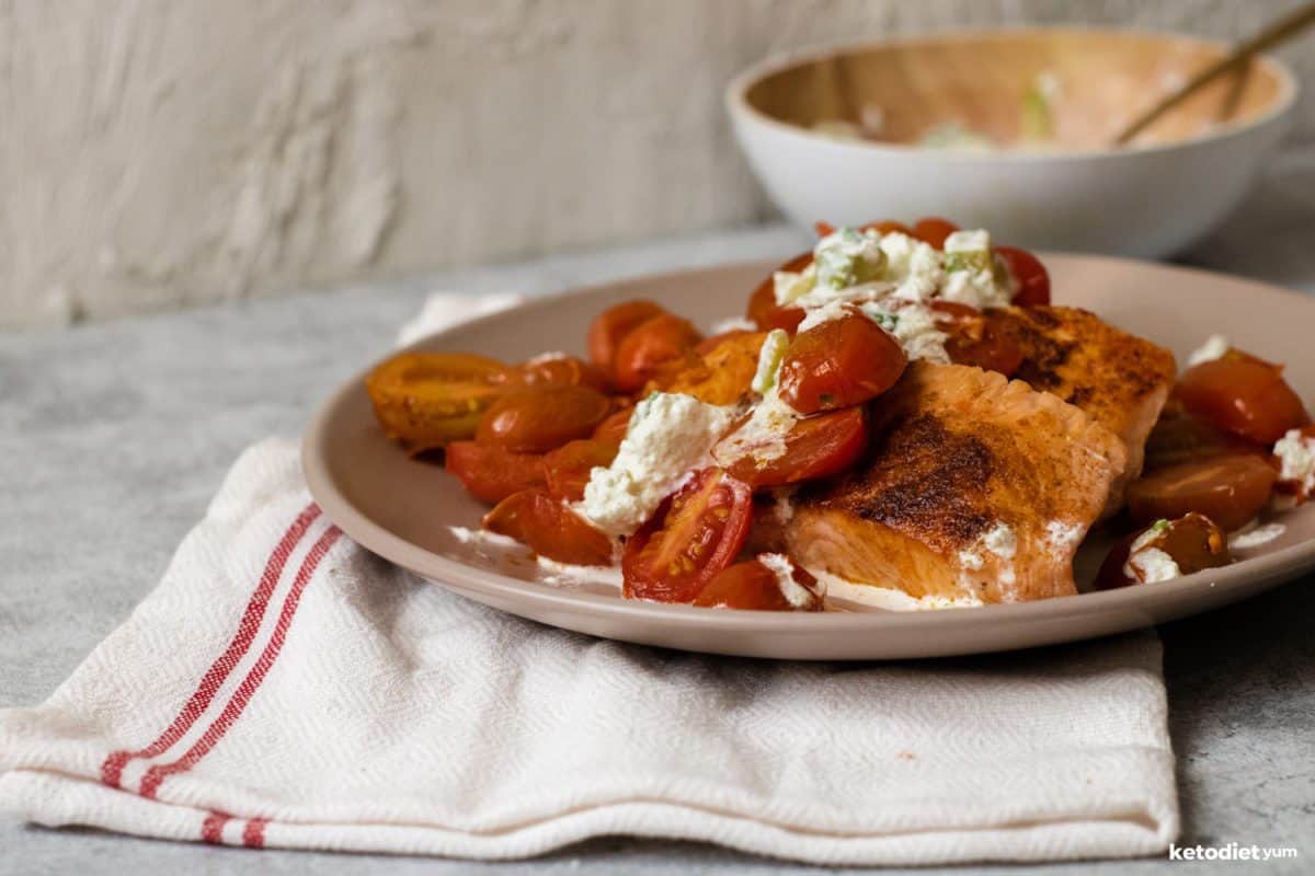 Salmon fillets, cherry tomatoes and goat cheese on a plate under a tea towel