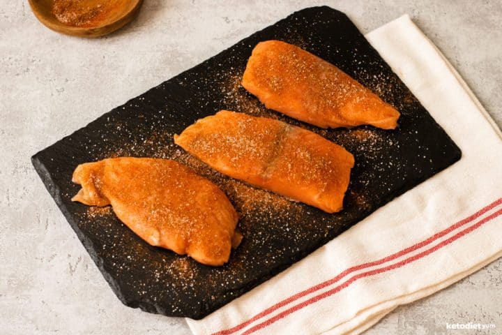 Coating salmon fillets with chili powder, cumin and salt ready to sear in a non-stick pan
