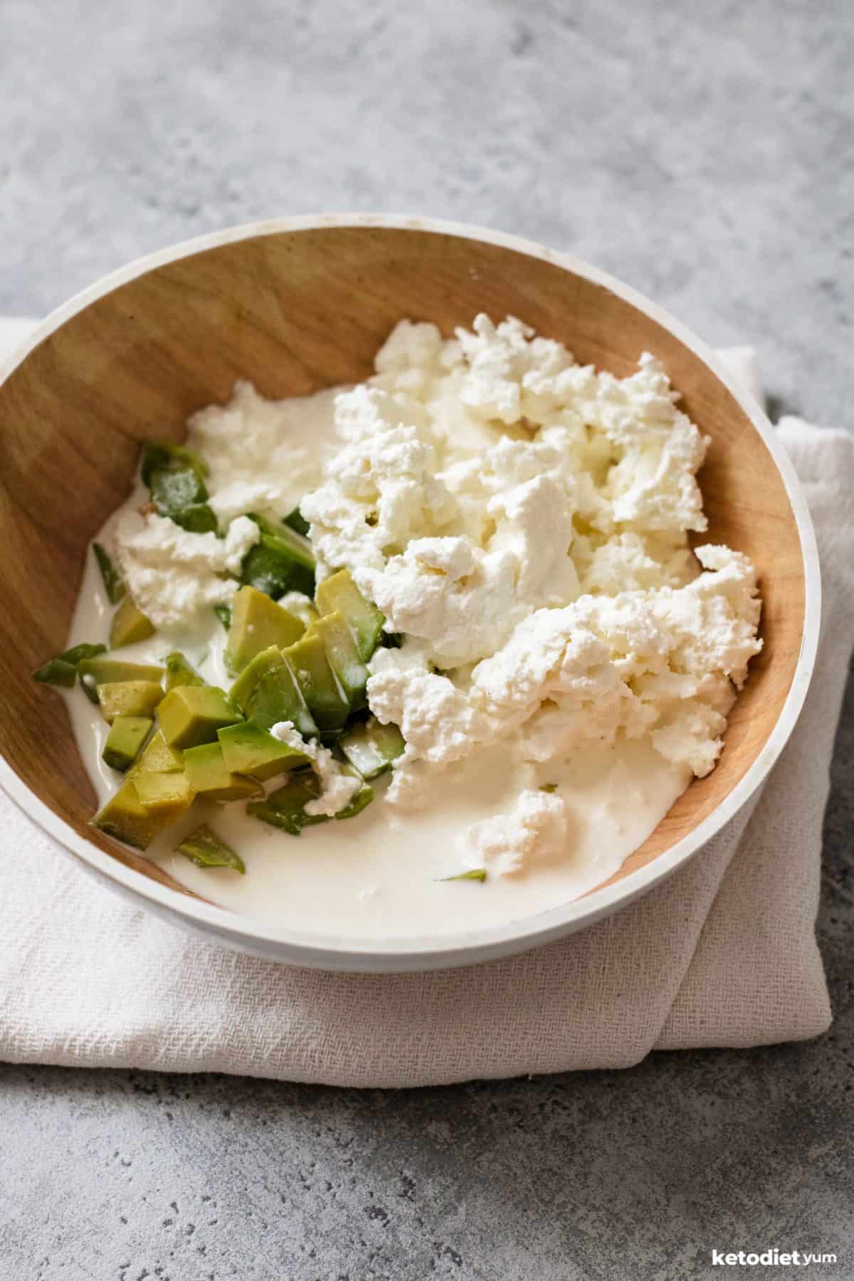 Sour cream, goat cheese and diced avocado in a bowl