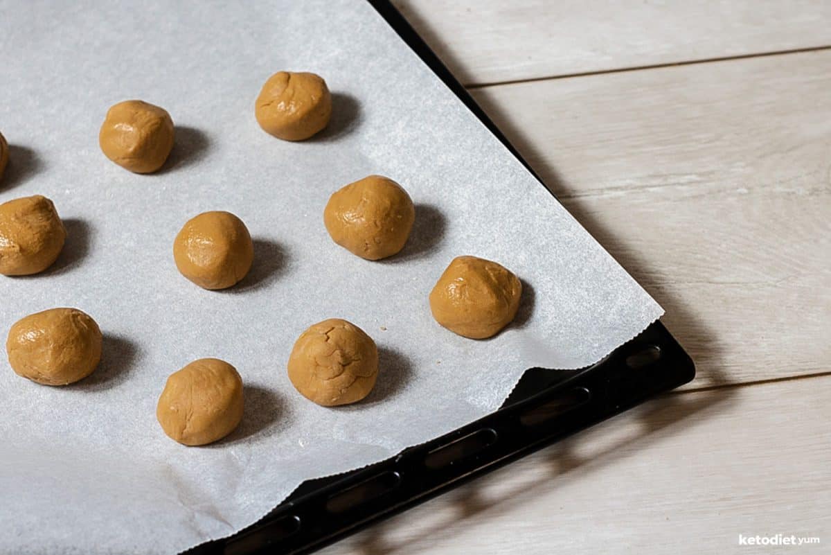 Rolling peanut butter energy balls and placing them on a lined baking pan ready to set in the fridge