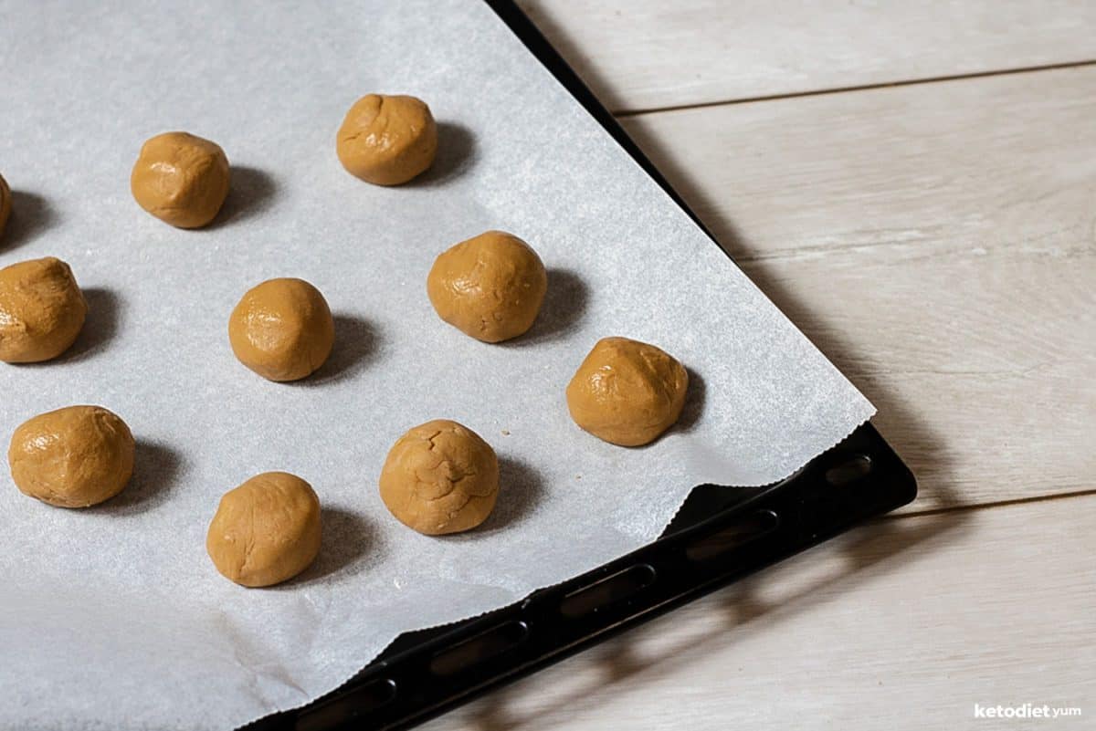 No Bake Peanut Butter Energy Balls Rolling peanut butter energy balls and placing them on a lined baking pan ready to set in the fridge