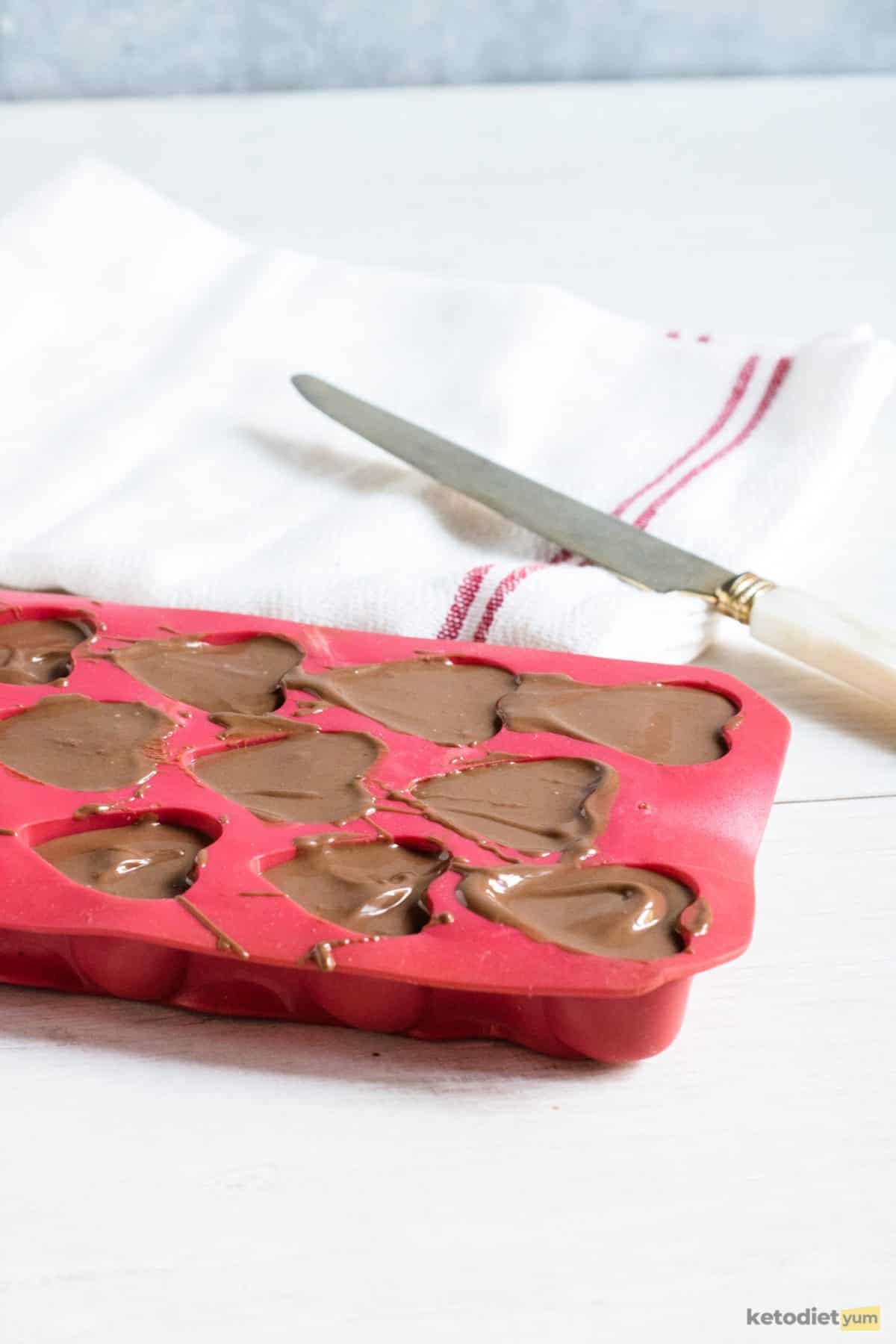 3 Ingredient Keto Chocolate Hearts Pouring the remaining chocolate mixture into the heart-shaped silicone mold