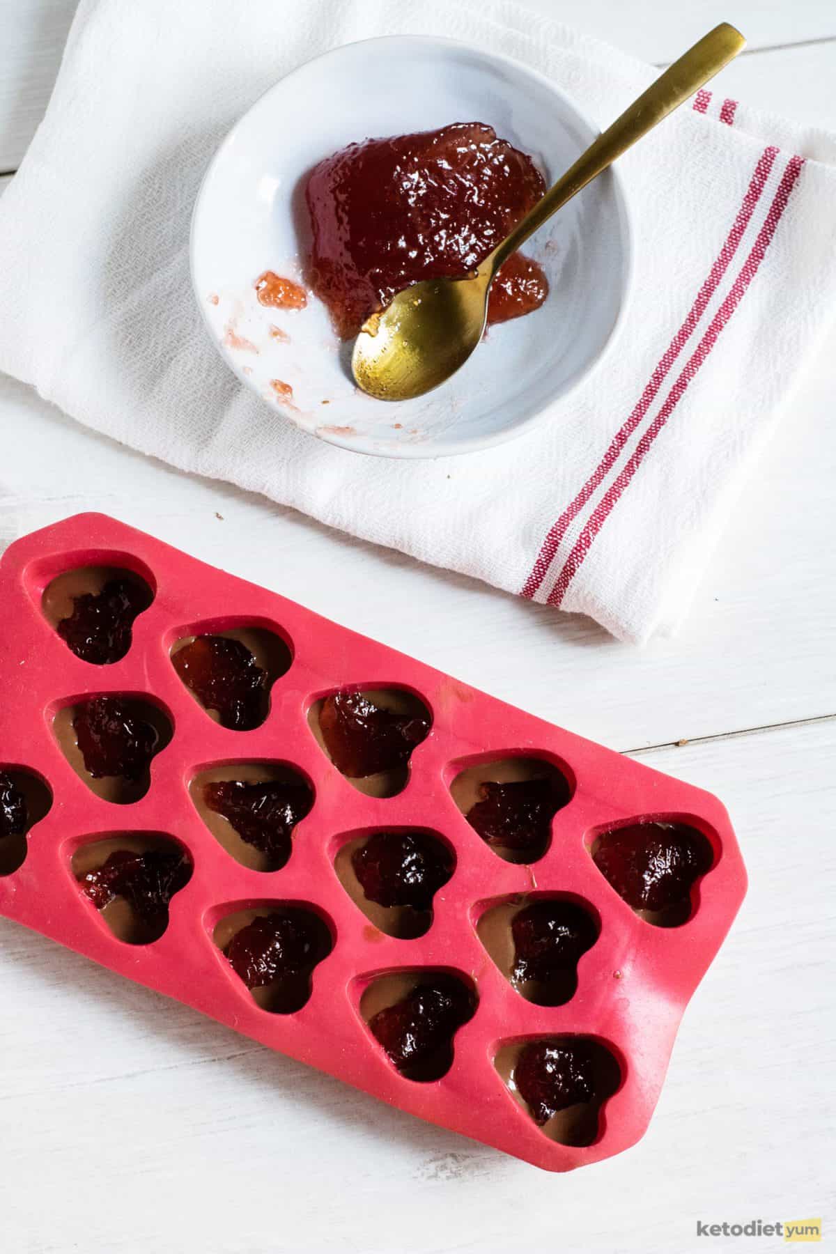 Adding strawberry jelly to the center of each chocolate heart