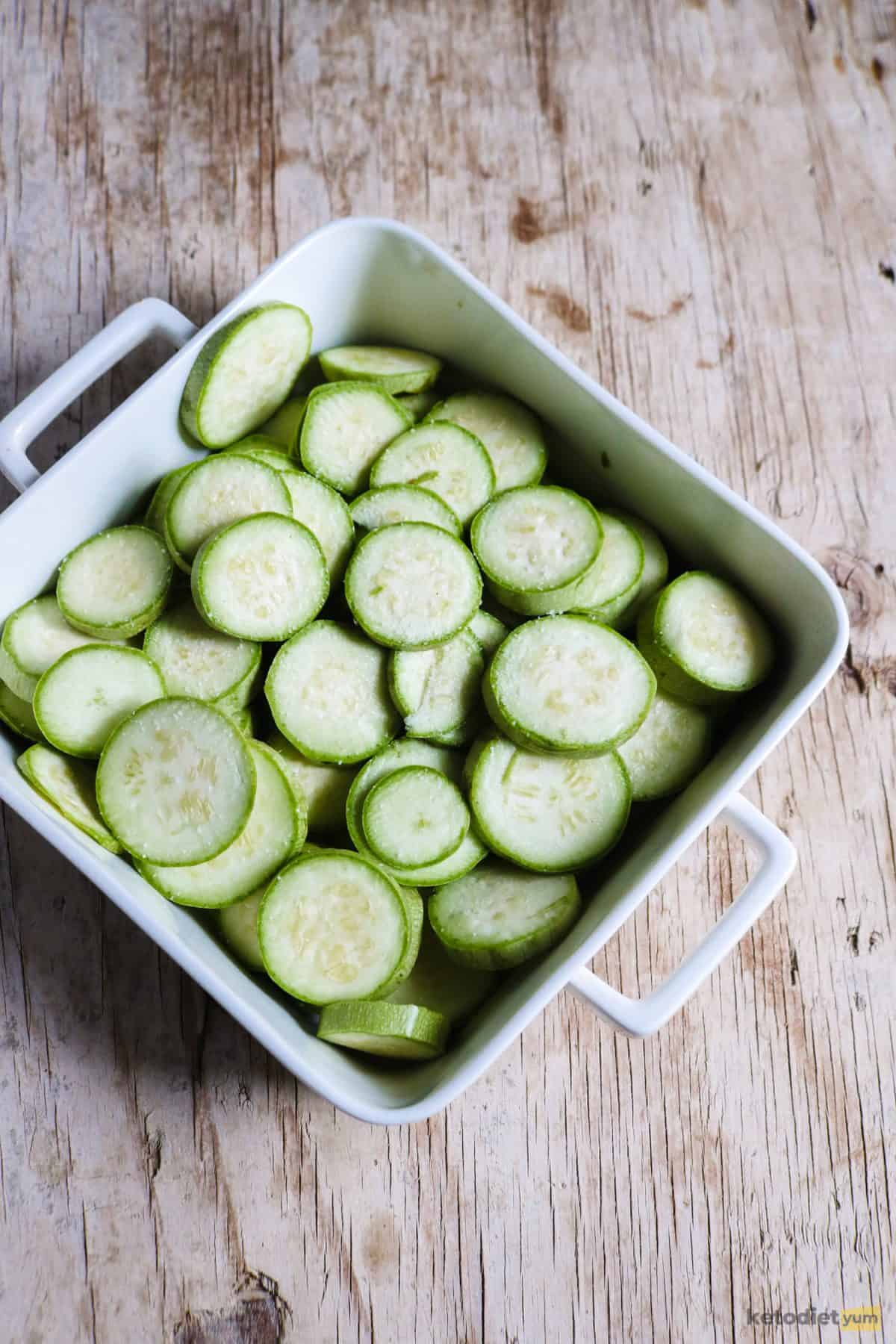 Zucchini slices placed in a layer in a greased baking dish