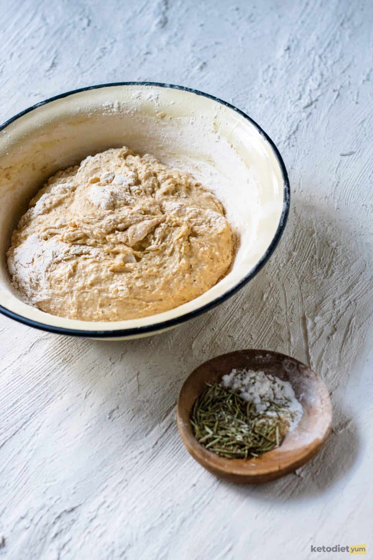 Keto focaccia bread dough in a mixing bowl ready to be transferred to a baking pan