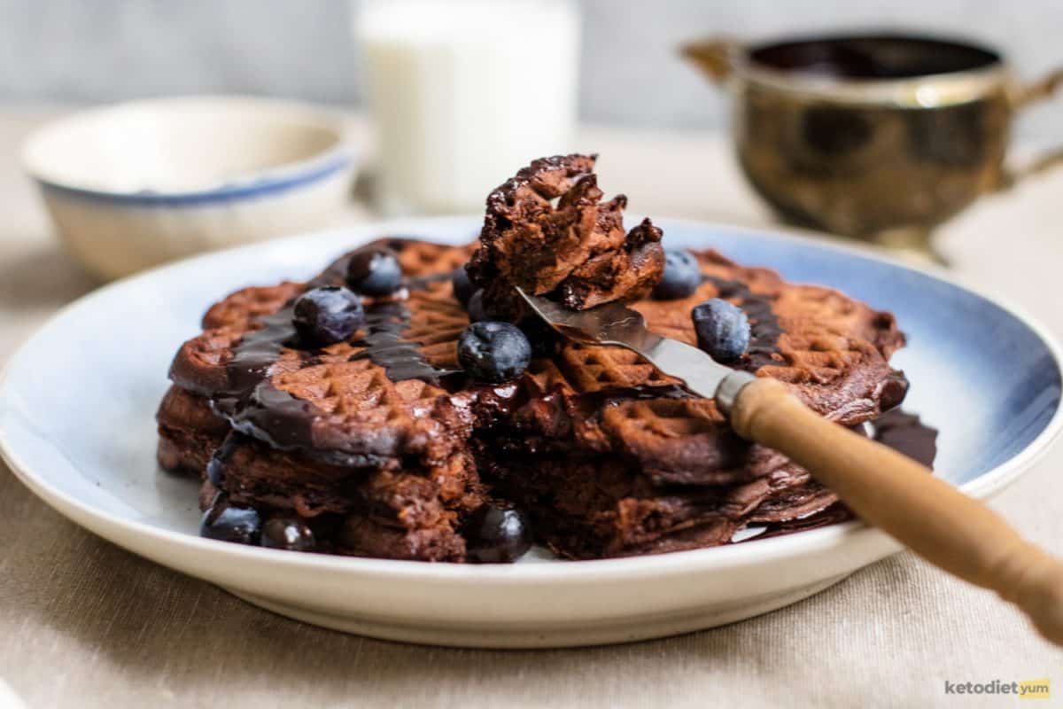 A keto chocolate chaffle topped with sugar-free chocolate syrup and blueberries
