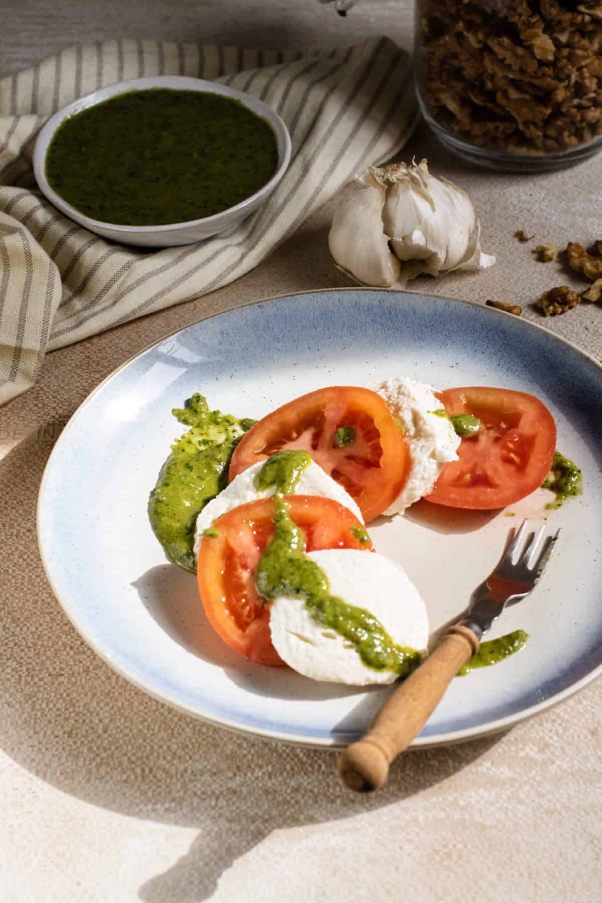 Keto tomato mozzarella salad topped with a homemade pesto