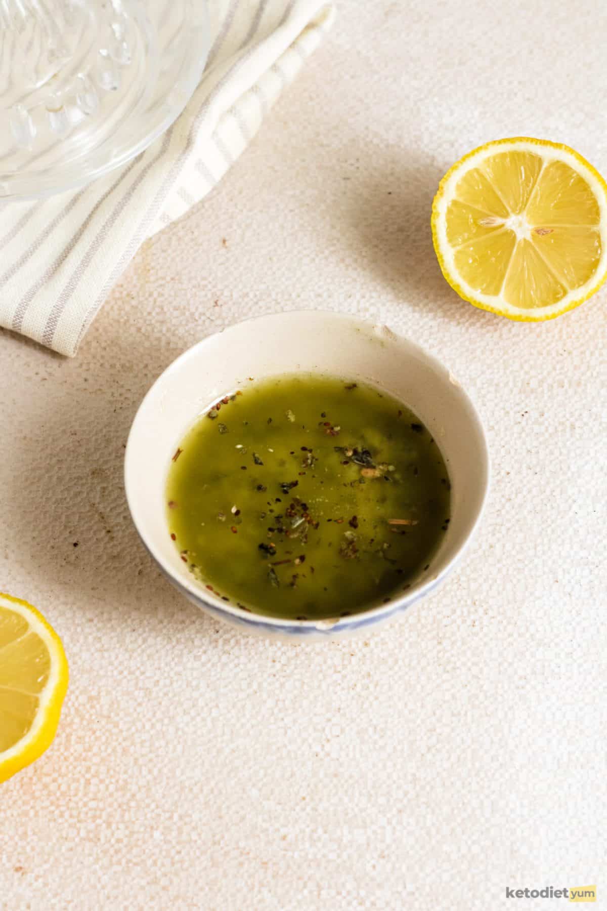 A super easy vinaigrette in a white bowl made with lemon juice, olive oil, Dijon mustard, basil, salt and pepper