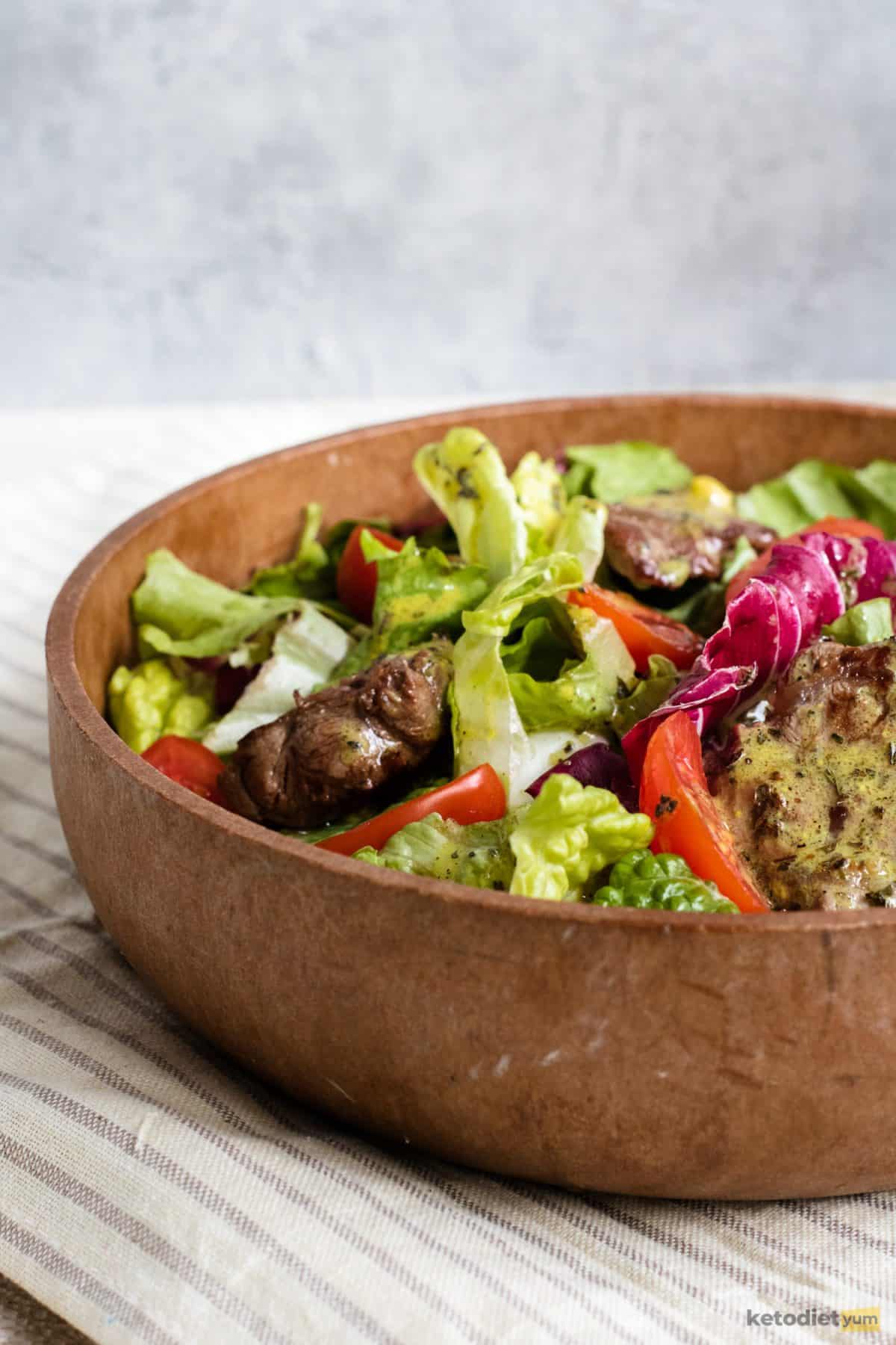 Low carb steak salad in a bowl with sirloin steak, mixed greens and drizzled with a lemon basil vinaigrette