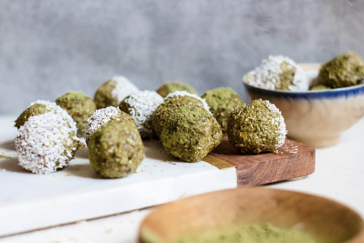 Matcha energy balls on a serving plate garnished with shredded coconut and matcha powder