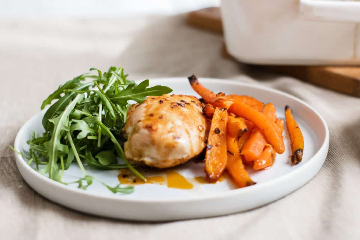Chili Garlic Roasted Chicken and Carrots Roasted chicken and vegetables (carrots) and a side salad on a white plate