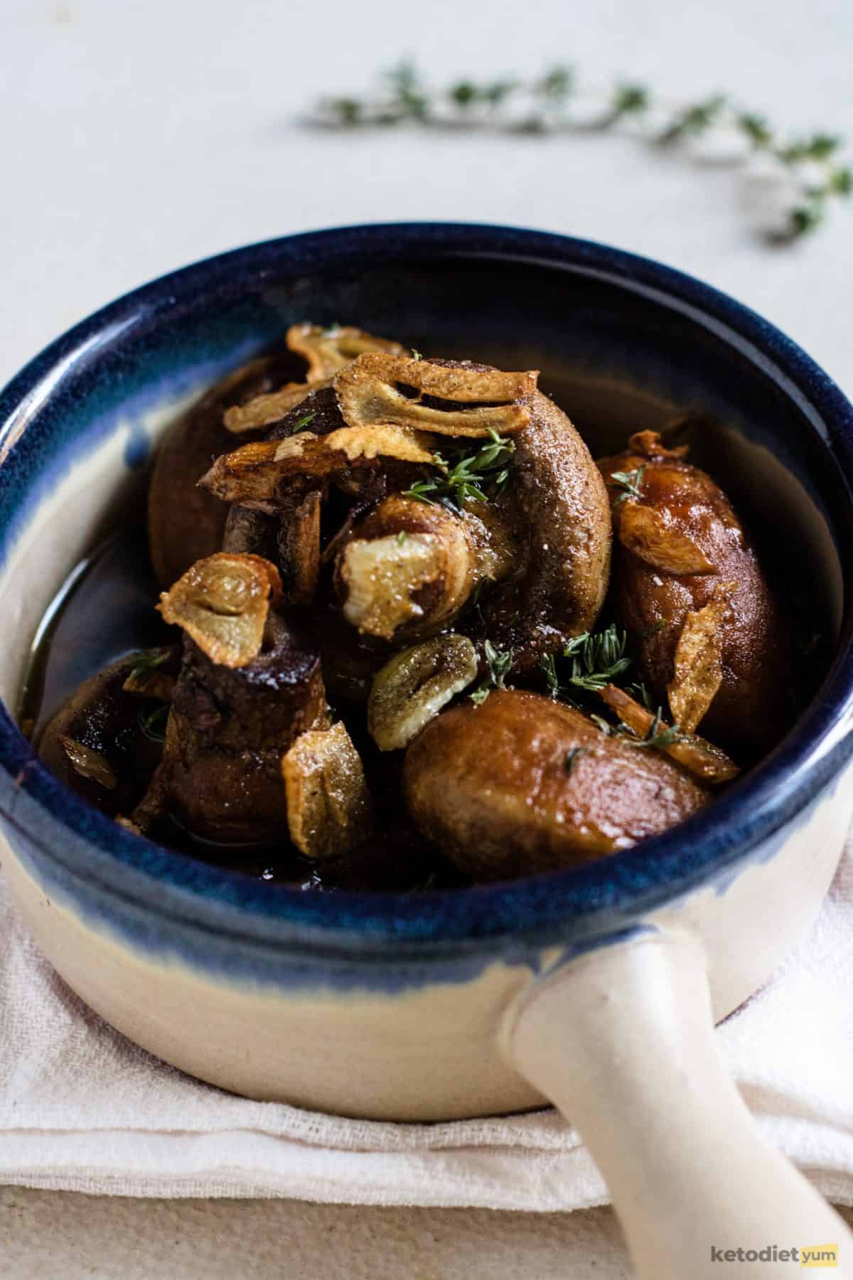 Button mushrooms in a herb garlic butter in a serving bowl