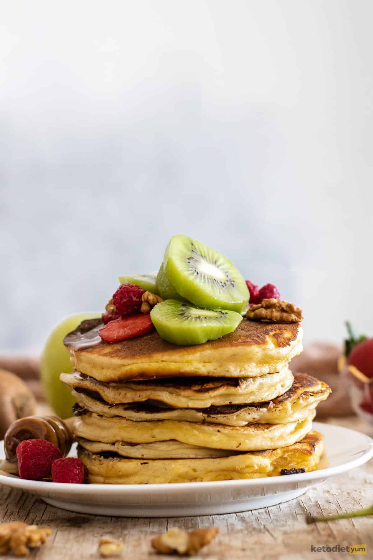 Fluffy keto pancakes topped with sliced strawberries and kiwifruit
