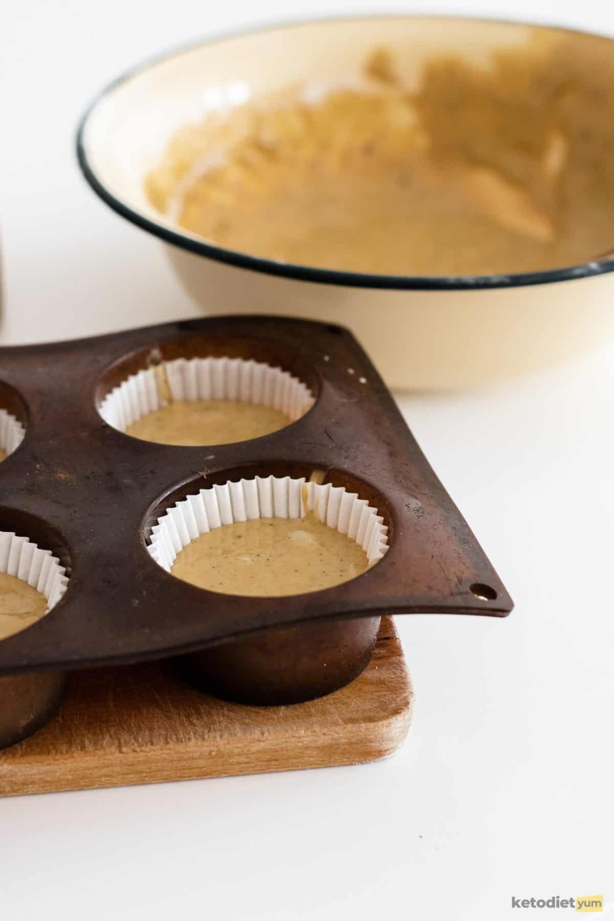 Pouring matcha cupcake batter into a lined muffin tray