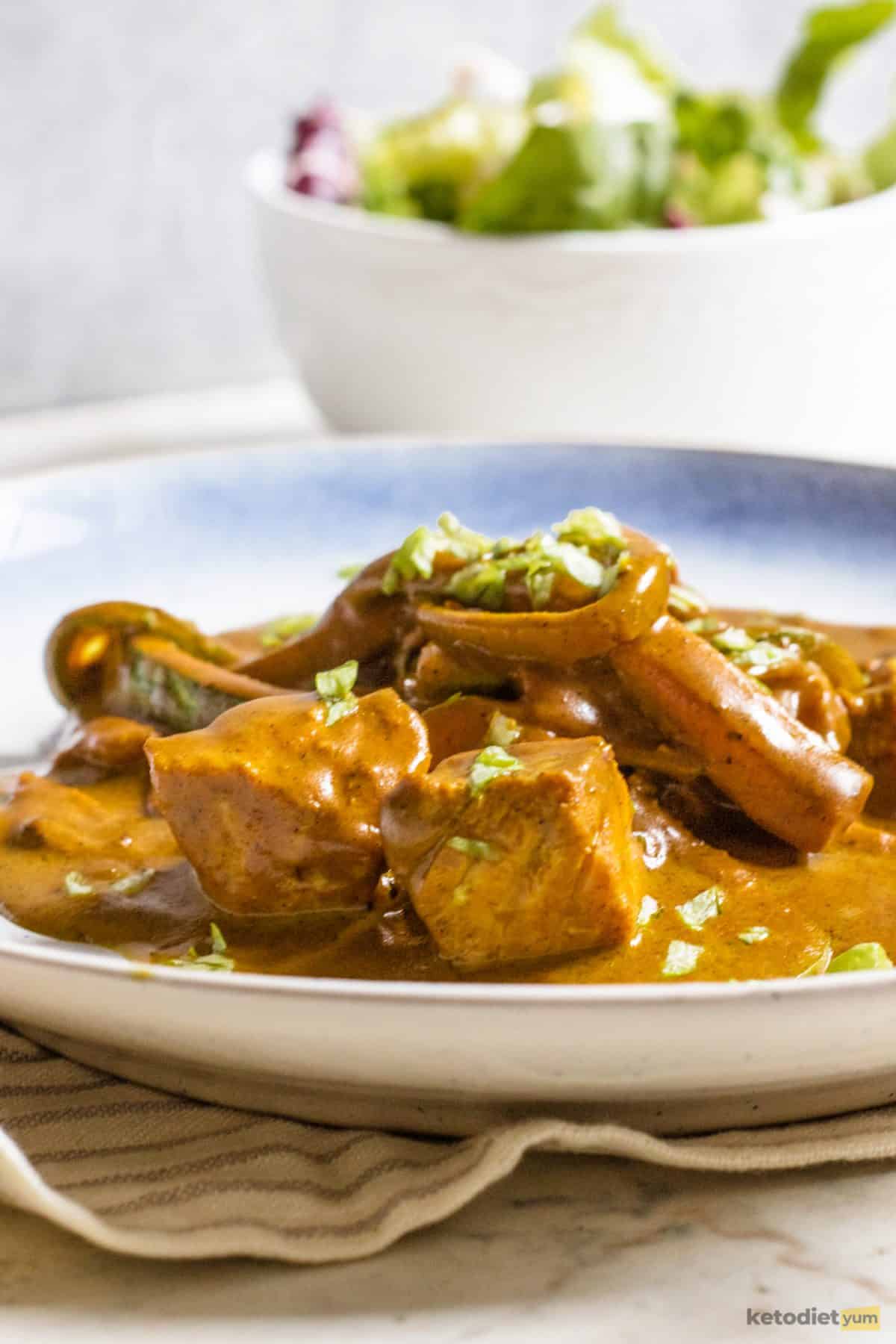 A rich, creamy and filling low carb salmon coconut curry served on a white and blue plate