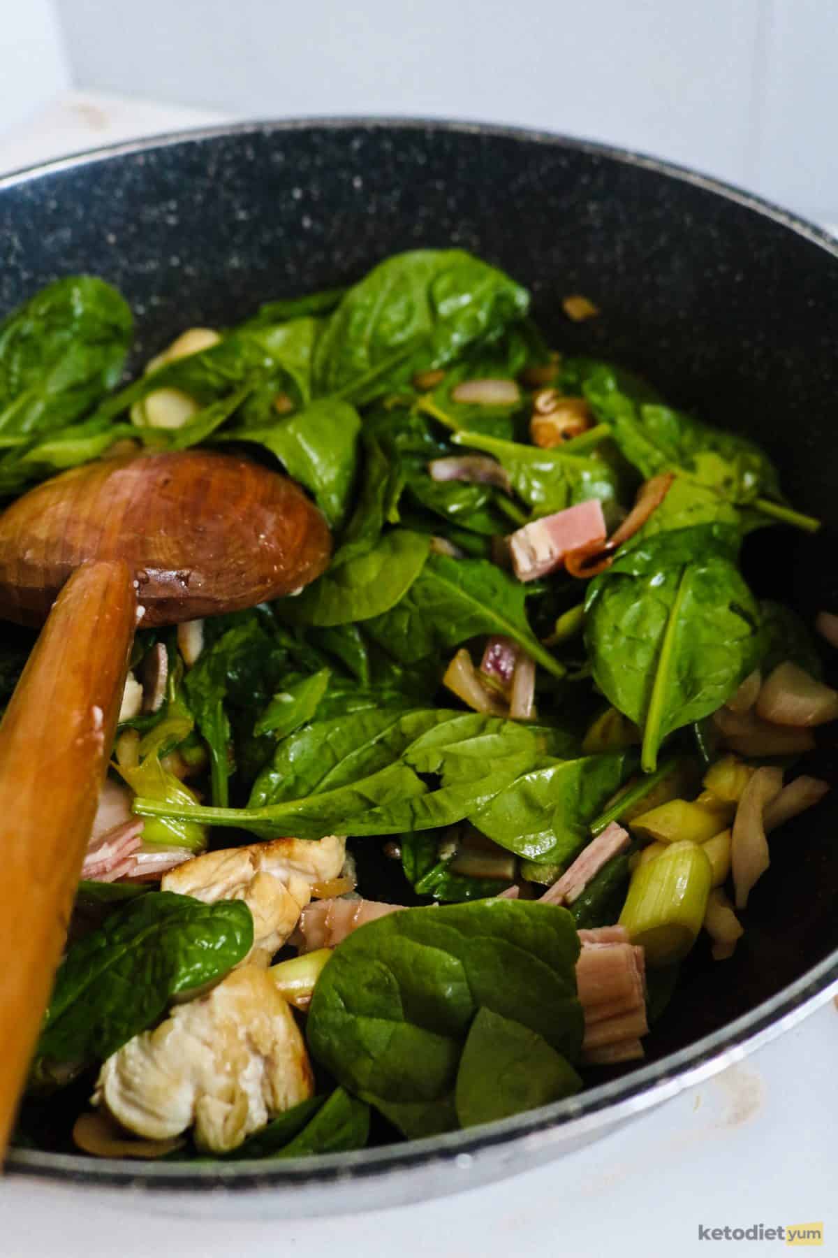 Adding spinach and bacon to sautéd chicken, onions and leeks.