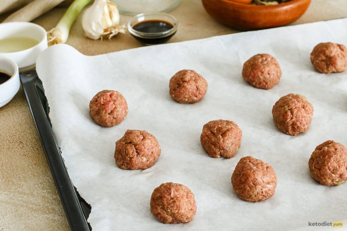 Ground pork meatballs on a lined baking tray ready to go into the oven