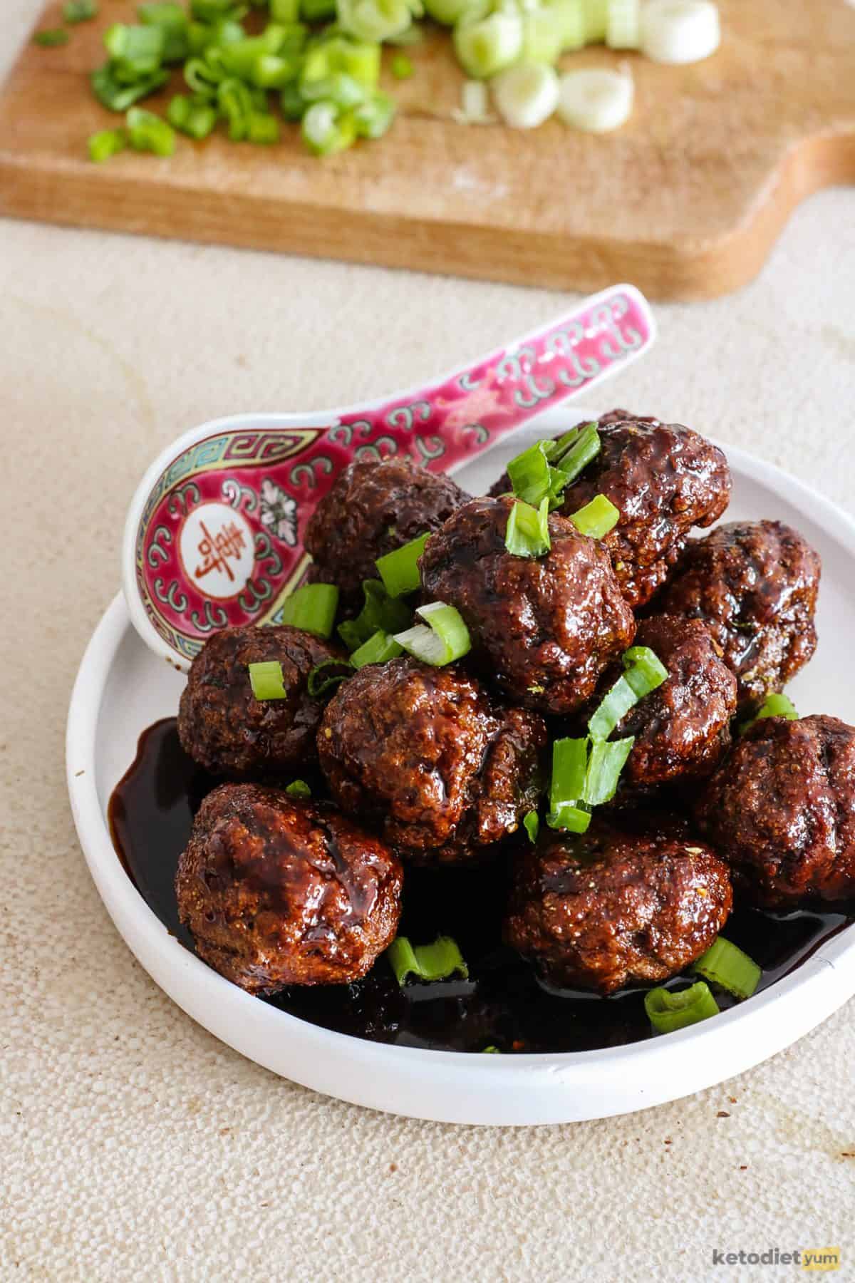 Kung pao meatballs garnished with green onion served in a white bowl